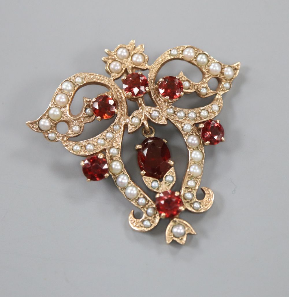 A Victorian style 9ct gold, garnet and seed pearl set openwork scrolling drop pendant, 40mm, gross 9 grams.